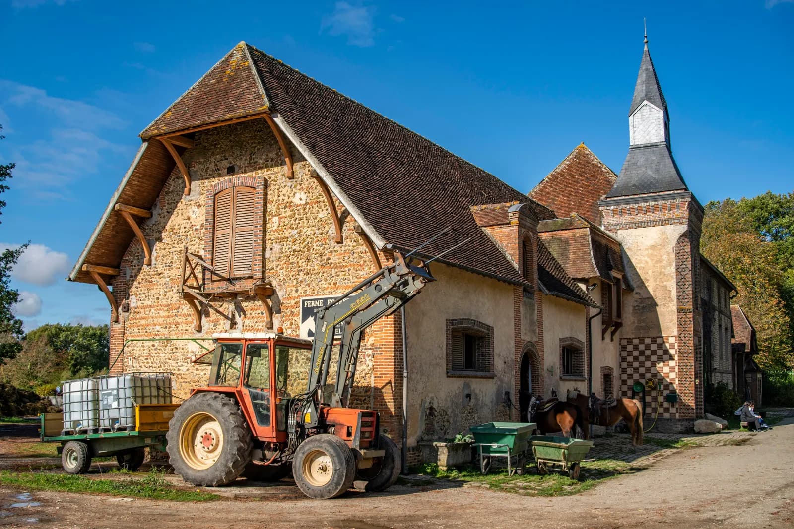 Corps de ferme en pierre et tracteur dans la cour d'une exploitation agricole en diversification