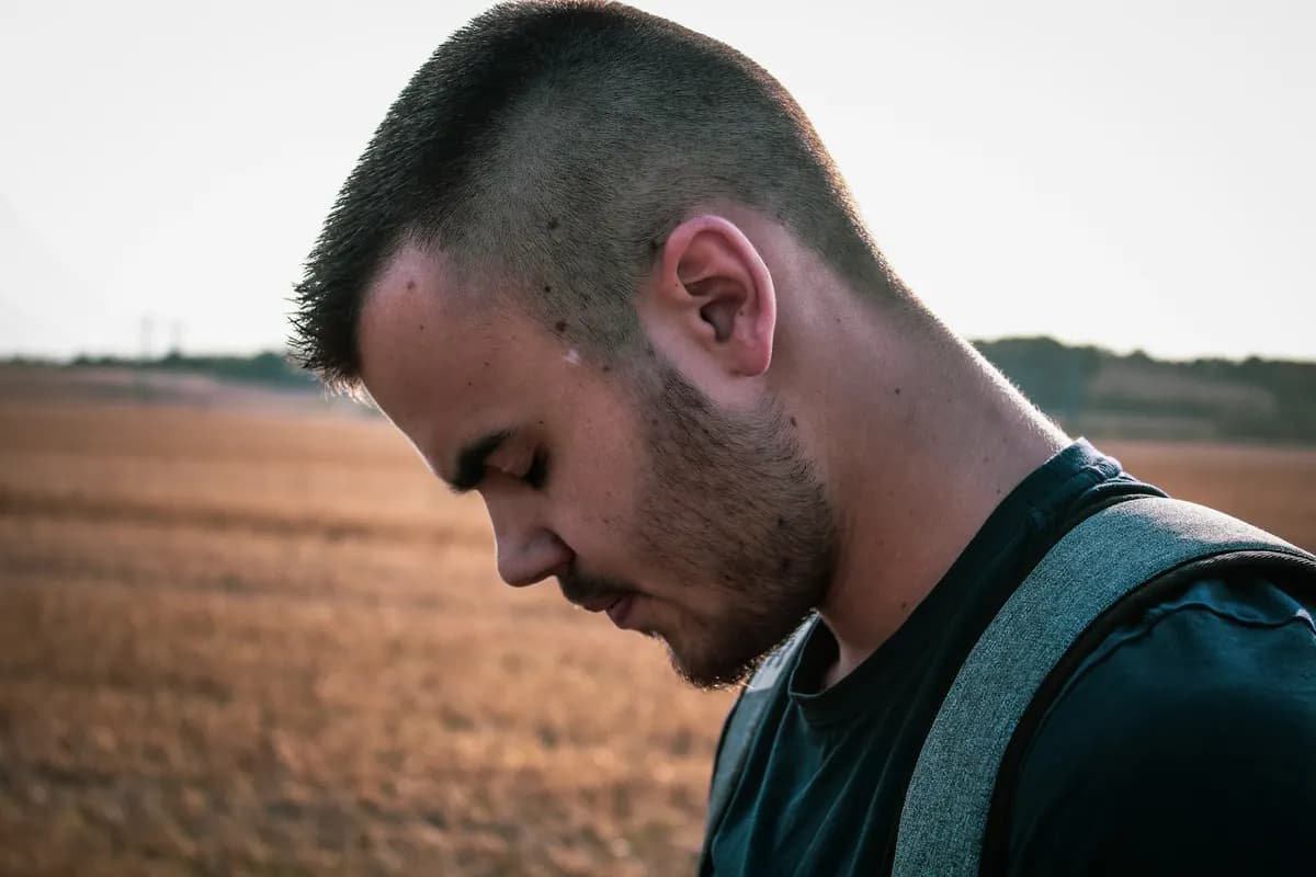 Jeune agriculteur pensif devant un champ, réfléchissant aux forces et faiblesses de son projet