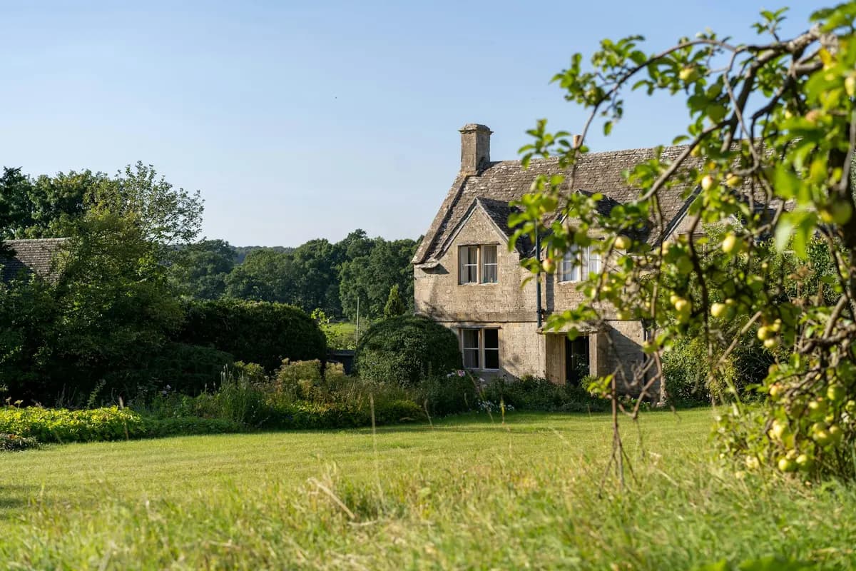 Maison de campagne en pierre entourée de verdure, pouvant accueillir un gîte rural
