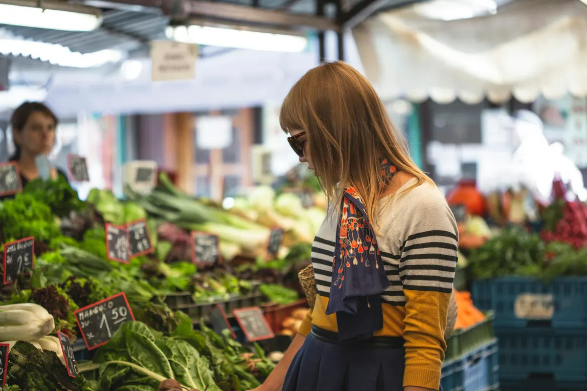 Cliente choisissant des légumes frais sur un étal de producteurs locaux