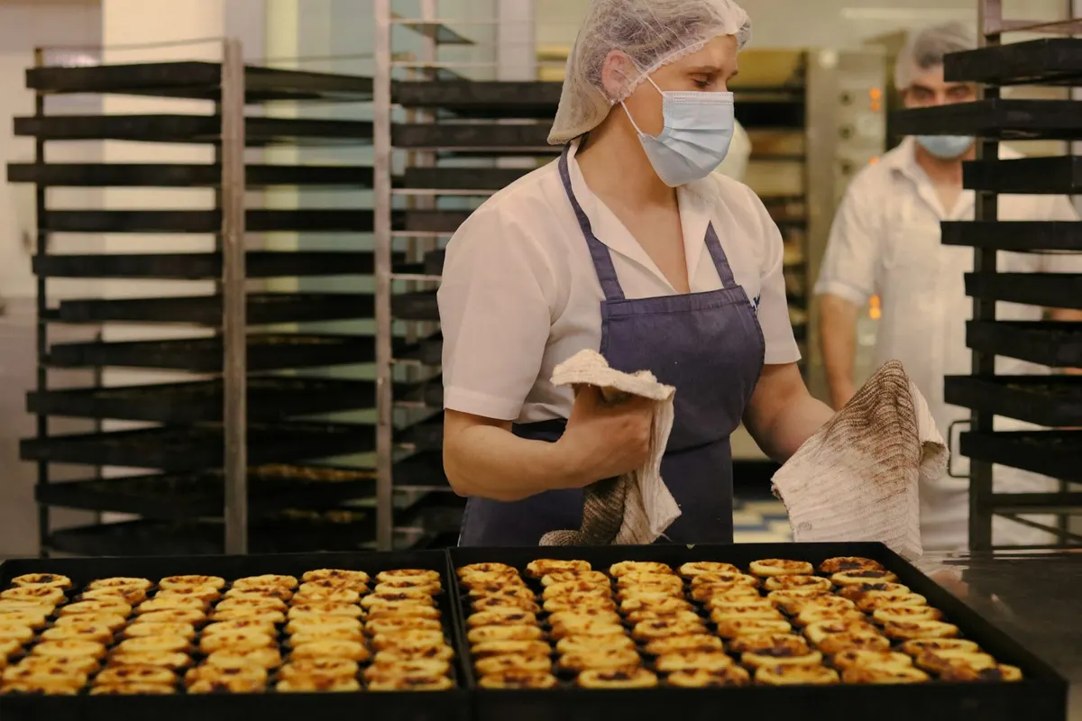 Boulangère en charlotte et masque dans un fournil, atelier contrôlé par les services vétérinaires de la DDPP